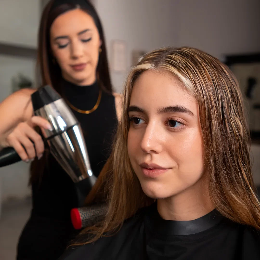 At-home hairstylist providing a blowout service to a woman as part of the LetMeGlam on-demand membership