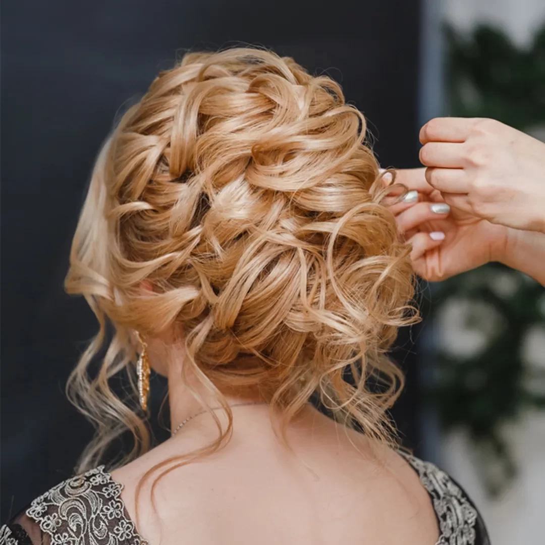 Hairstylist using professional equipment to style a client's hair in the comfort of their own home.